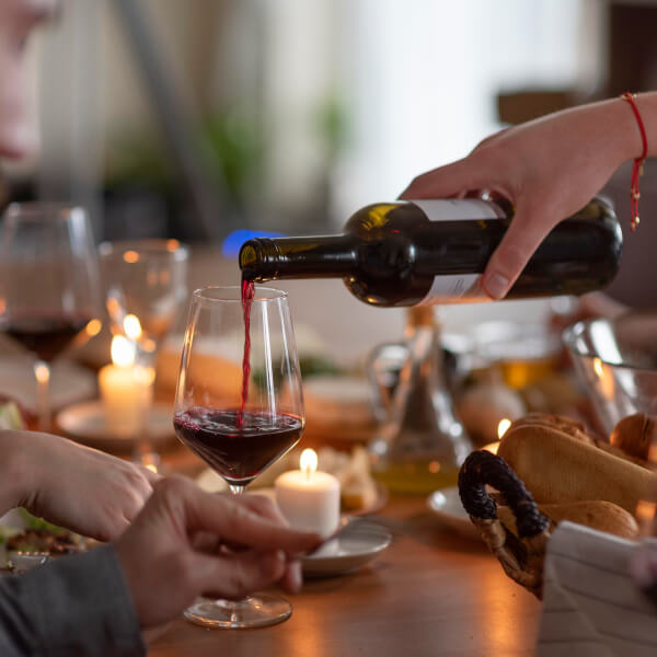 Una persona sirviendo vino en una copa, representando la experiencia de la ruta del vino.
