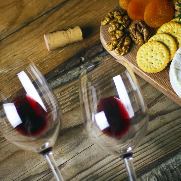 Mesa de madera con una copa de vino y un plato de comida, representando la gastronomía de Vinos mexicanos.