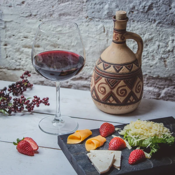 Un plato con queso, fresas y una copa de vino mexicano.